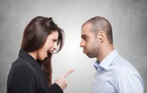 une femme critique un homme de manière agressive en le montrant du doigt